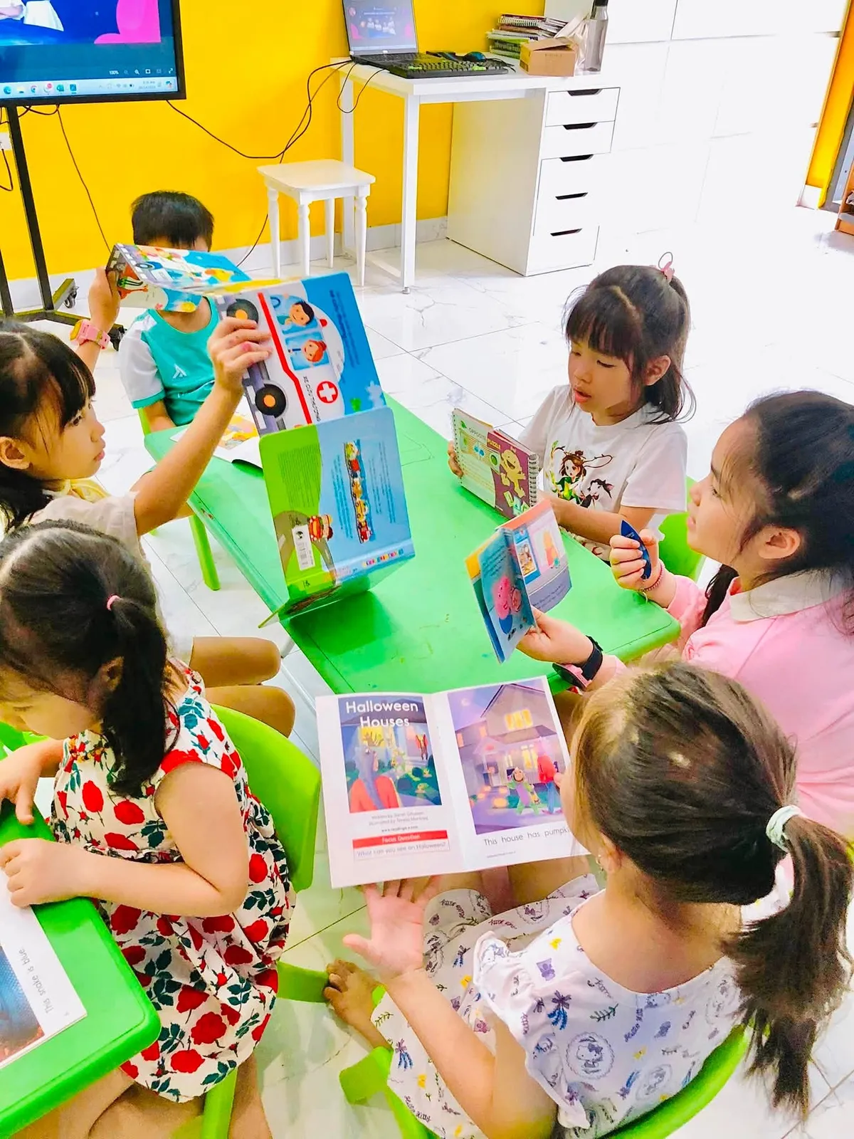 Một bạn nhỏ giơ cao cuốn sách khoe với các bạn trong giờ đọc tại Clever Junior Long Biên